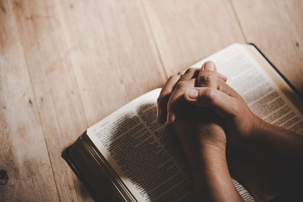 espiritualidade-e-religiao-as-maos-postas-em-oracao-sobre-uma-biblia-sagrada-na-igreja-conceito-de-fe-1024x683 Por que Oramos e Por Que em Nome de Jesus?