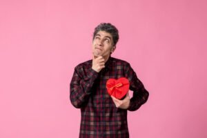 "Nada é errado se te faz feliz". Será mesmo? jovem-segurando-um-coracao-vermelho-em-forma-de-presente-na-parede-rosa
