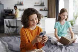 O Google está ensinando seu filho sobre sexo. E você? (O que tenho aprendido como mãe de 4) mãe na cozinha enquanto crianças estão no celular