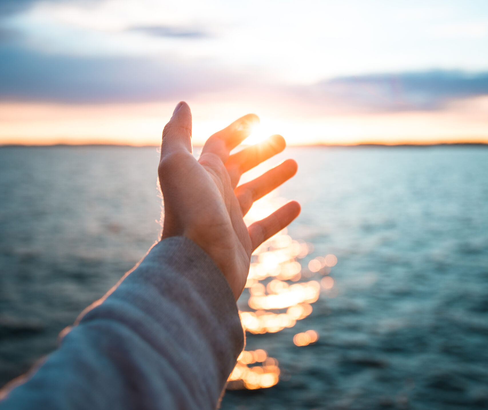 tiro-vertical-de-uma-mao-com-o-belo-mar-ao-fundo-durante-os-sois-scaled-e1766584124435 O Que Realmente Significa "Ser Redimido pelo Sangue do Cordeiro"?