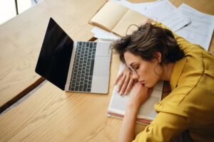 Top view of young tired woman dreamy asleep on desk with laptop