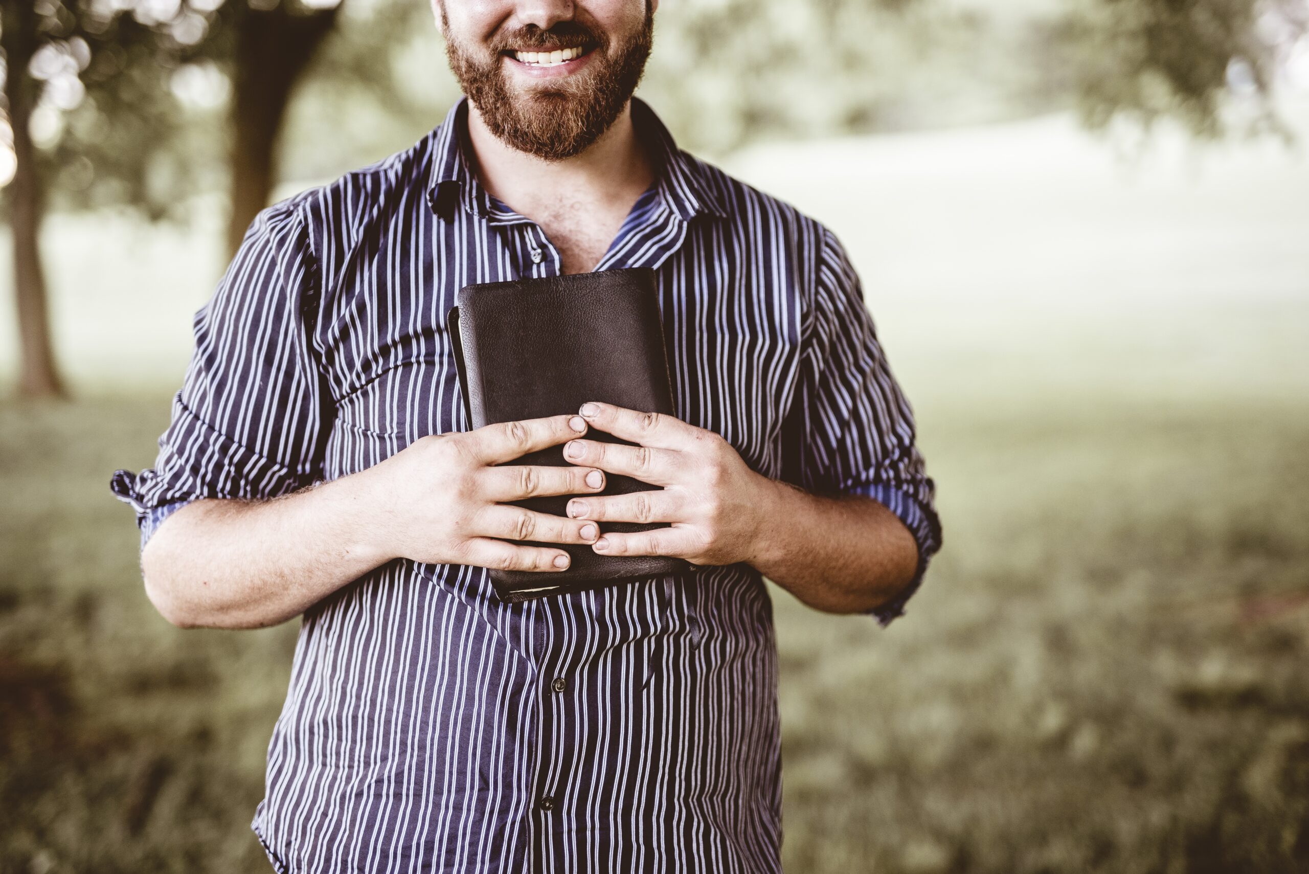 closeup-shot-male-smiling-holding-bible-with-blurred-background-scaled Mudar por fora ou florescer por dentro? O segredo que às vezes esquecemos