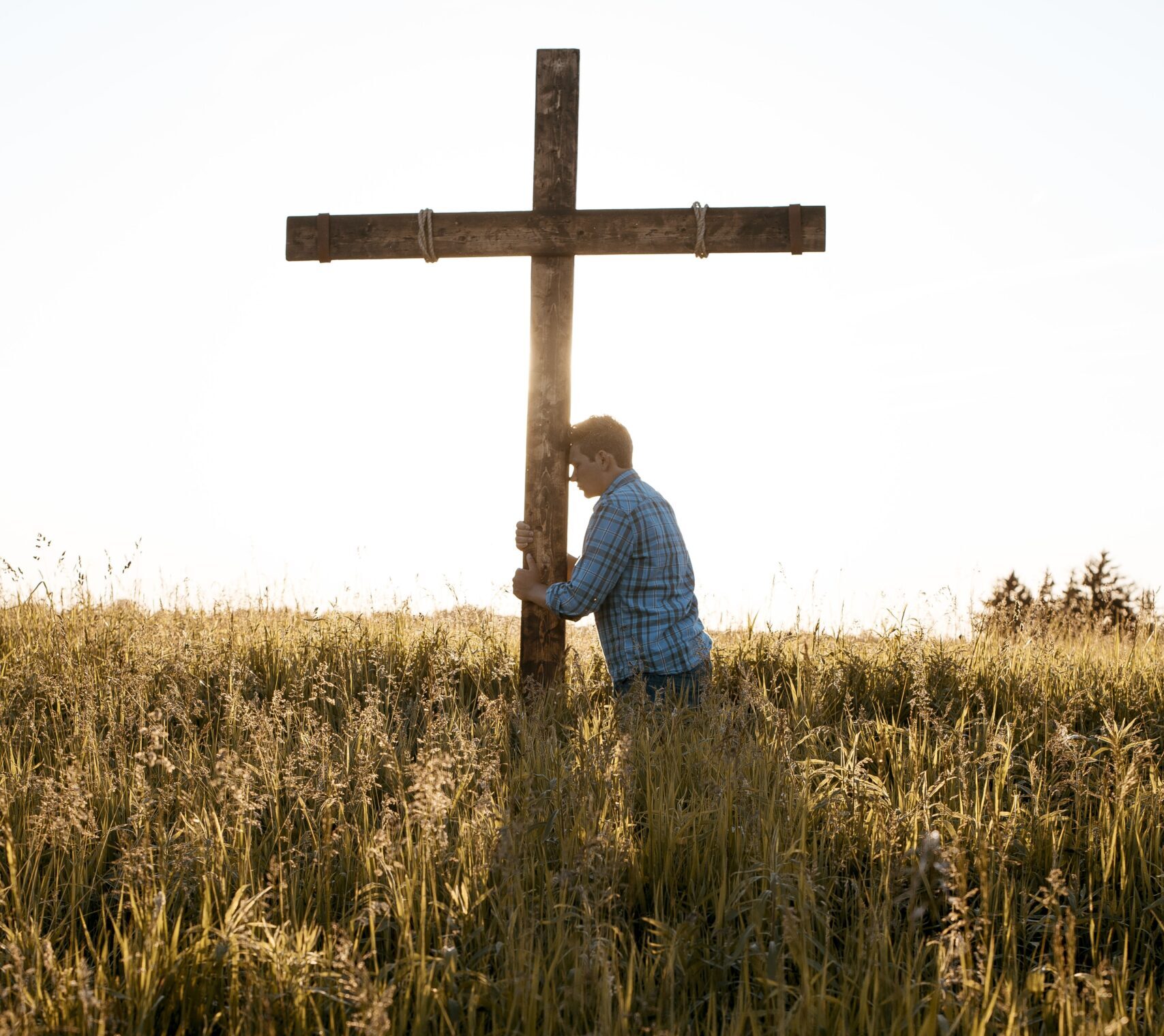 vertical-shot-male-with-his-head-against-wooden-cross-grassy-field-scaled-e1768862967649 O Gemido das Nações: Por que o mundo parece estar à beira de um colapso?